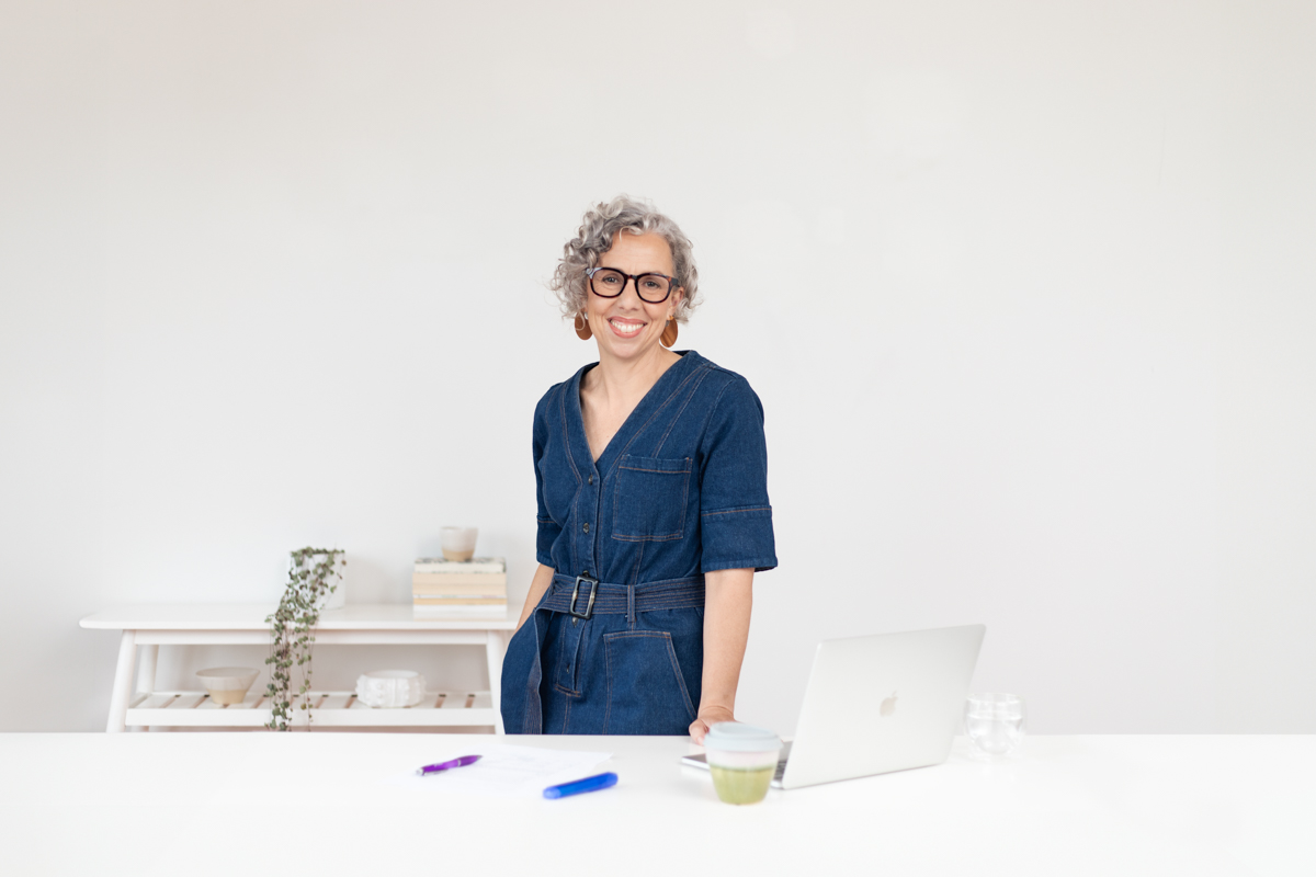 Image of Jess standing a a desk smiling